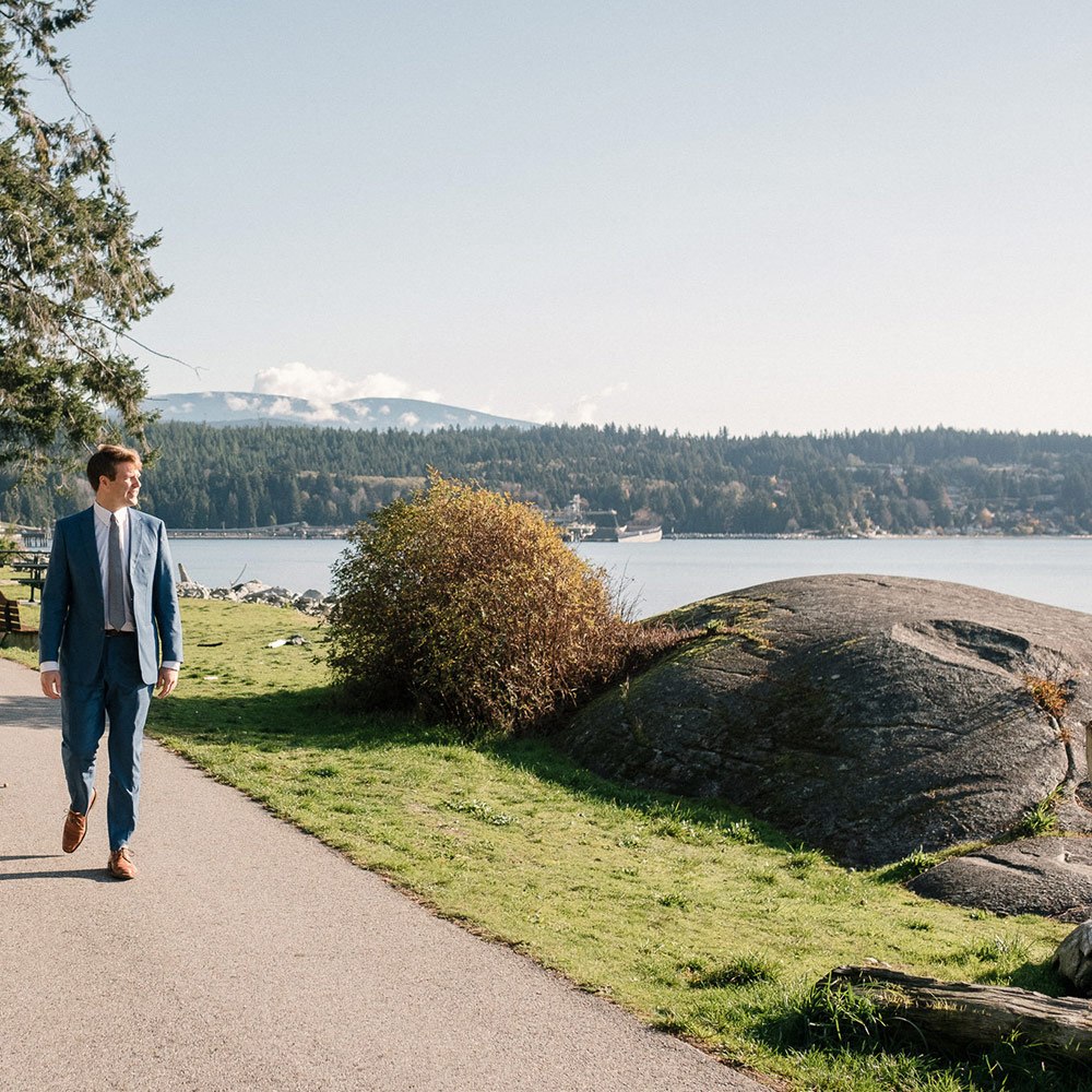well-dressed man walking along path at waterfront